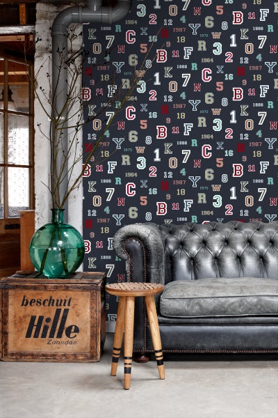 Wohnzimmer mit gemusterter Tapete, Ledersofa und Holzhocker