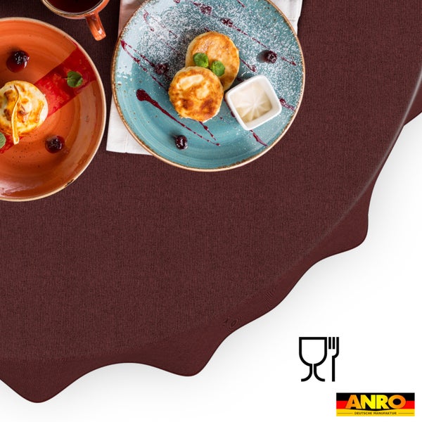 Strukturierte Tischdecke auf einem gedeckten Tisch mit Tellern und Speisen, lebensmittelecht, ANRO Logo.