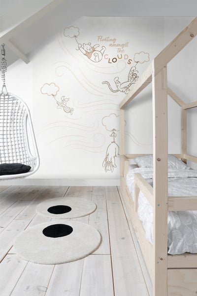 Kinderzimmer mit Holzbett, Hängesessel und Teppichen mit Punktmuster sowie Winnie Puh Wandtattoo