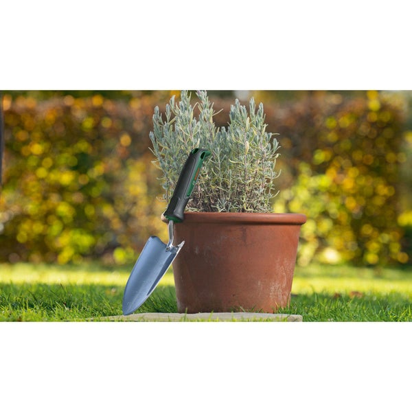 Blumentopf mit Pflanze und Gartenschaufel im Garten