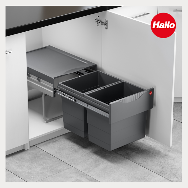 Hailo Abfalltrennsystem zum Auszug mit zwei grauen Mülleimern in einem weißen Küchenunterschrank. Hailo Logo.