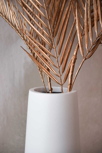 Goldene getrocknete Palmwedel in einer weißen Vase.
