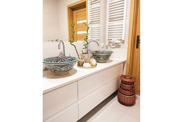 Badezimmer mit zwei Waschbecken in Schüsselform und weißen Badmöbeln