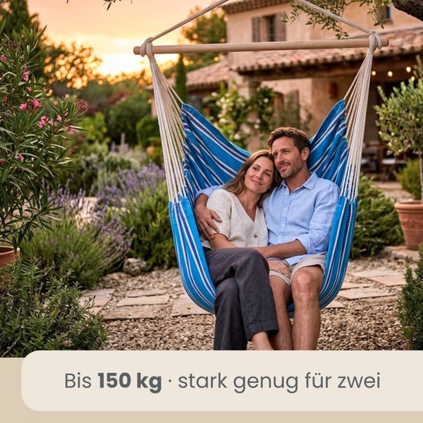 Ein Paar in einem blau-weiß gestreiften Hängesessel aus Stoff mit Holzstab im Garten. Belastbar bis 150 Kilogramm.