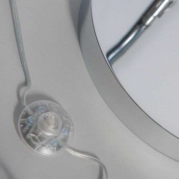 Durchsichtiger Fußschalter an einem Kabel mit einem Teil einer metallischen Leuchte.