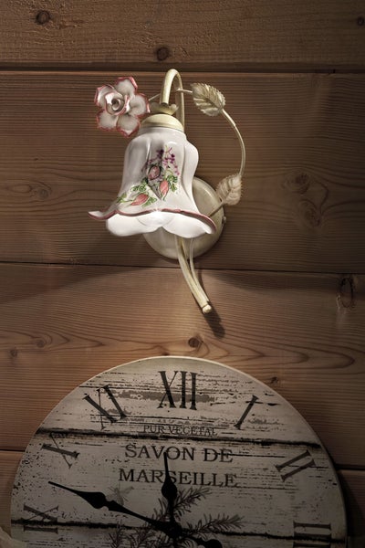 Wandleuchte mit Blumenapplikation und Wanduhr im Vintage-Stil vor Holzwand