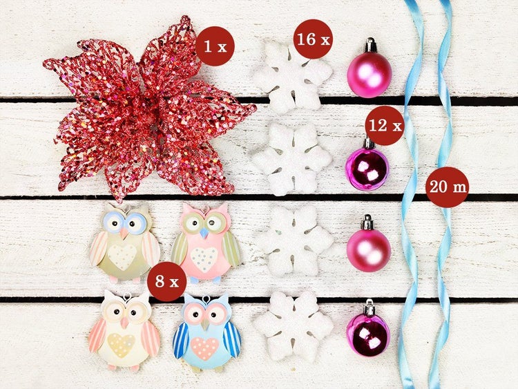 Set mit Weihnachtsschmuck bestehend aus einer glitzernden Blume, Eulenfiguren, Schneeflocken, Christbaumkugeln und Dekoband auf Holzuntergrund.