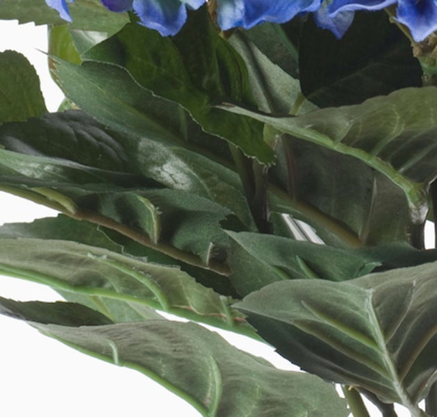 Detailansicht von grünen Blättern und blauen Blüten einer künstlichen Hortensie.