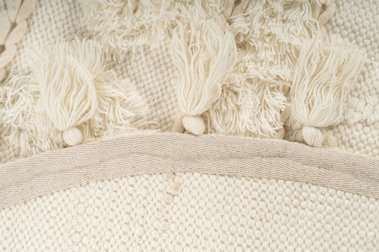 Detailaufnahme eines gewebten Teppichs mit Quasten und strukturierter Oberfläche.