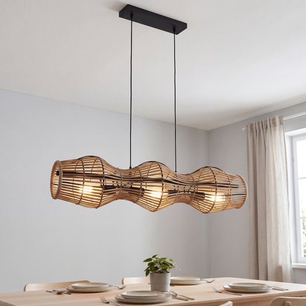Dreiflammige Pendelleuchte mit gewebtem Schirm aus Naturgeflecht in organisch geschwungener Form über einem Esstisch aus Holz.