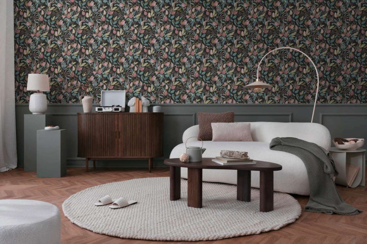 Wohnzimmer mit dunkler Blumengewebetapete, weißem Sofa, dunklem Holzsideboard und rundem Couchtisch auf Parkettboden in einem eleganten Interieur.