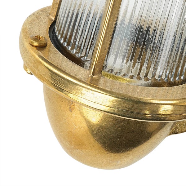 Detailaufnahme einer goldenen Wandleuchte mit geriffeltem Glas