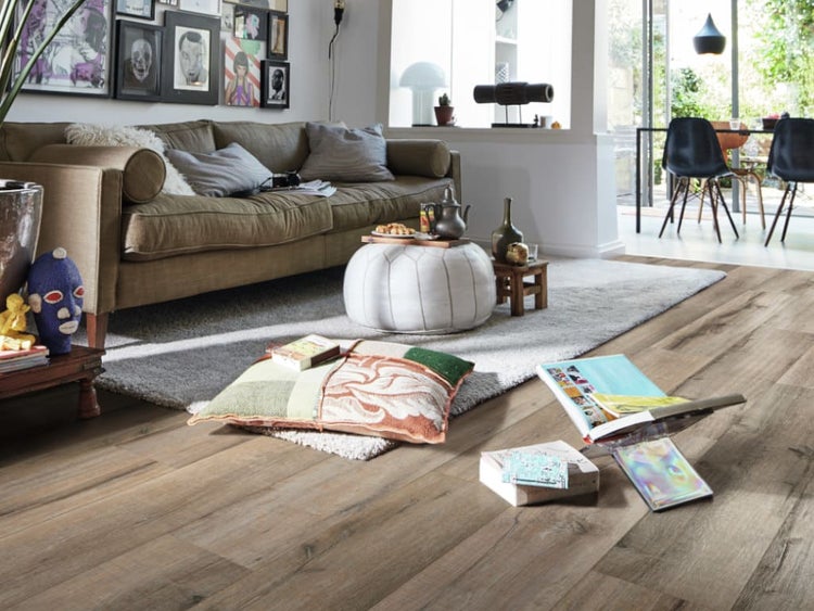 Wohnzimmer mit rustikalem Laminatboden in Holzoptik, das mit einem Sofa, Sitzkissen und moderner Dekoration gemütlich eingerichtet ist.