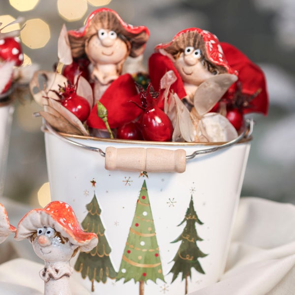 Weihnachtsdekoration mit zwei Pilzfiguren in einem verzierten Metalleimer mit Tannenbaummotiv