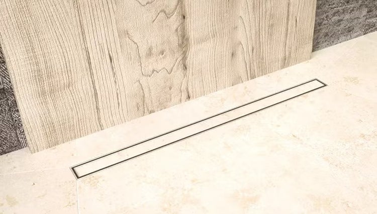 Bodenebene Duschrinne im Fliesenboden aus Natursteinoptik vor einer Wand mit Holzoptikfliesen.