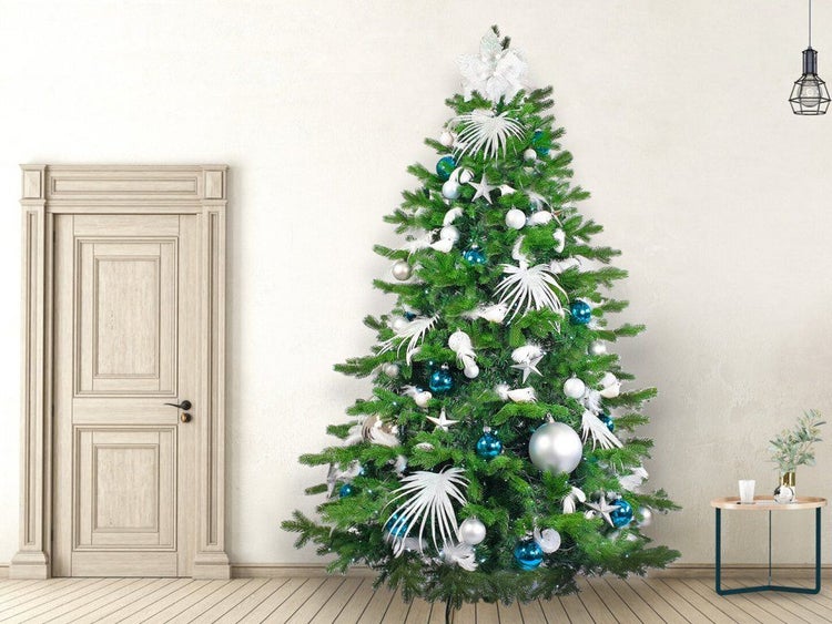 Geschmückter Weihnachtsbaum mit Kugeln und künstlichen Zweigen in einem hellen Wohnraum mit Holztür und Beistelltisch.