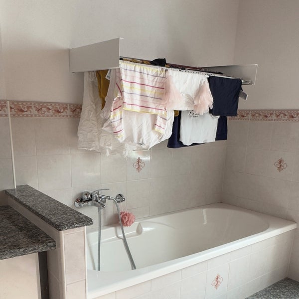 Badezimmer mit Badewanne und Wäscheständer an der Wand
