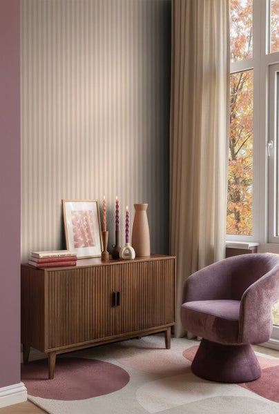 Wohnzimmer mit gestreifter Tapete, Holzkommode, Dekoration und Sessel