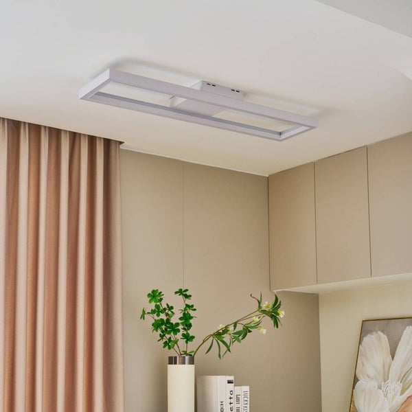 Moderne, rechteckige LED-Deckenleuchte in einem hellen, organisierten Wohnraum mit Vorhängen, Schränken und einer Pflanze in einer Vase.