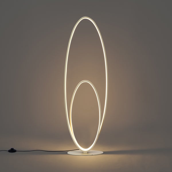 Moderne LED Stehleuchte mit zwei ineinandergreifenden ovalen Ringen, flachem runden Sockel und Fußschalter.