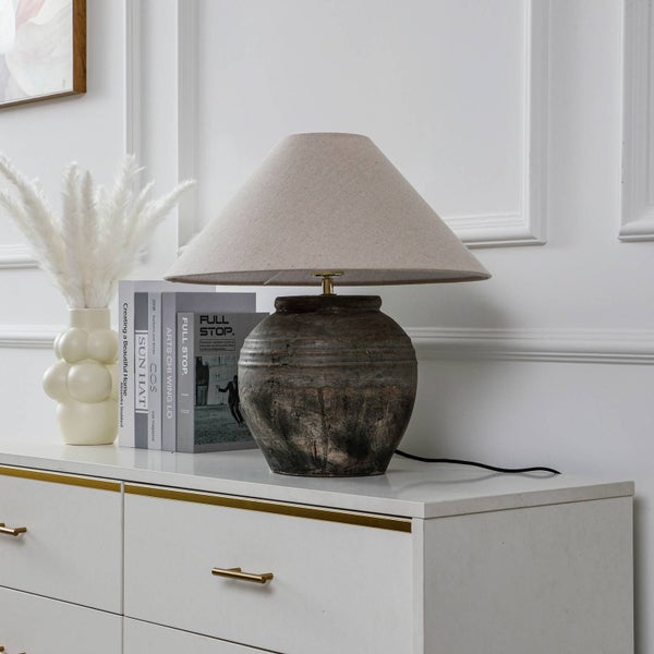 Dekorative Tischleuchte mit konischem Lampenschirm auf Kommode