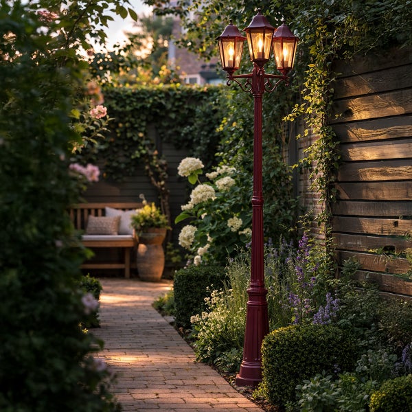 Eine dreiflammige nostalgische Gartenlaterne in einem üppig bepflanzten Garten mit gepflastertem Weg und gemütlicher Sitzgelegenheit.