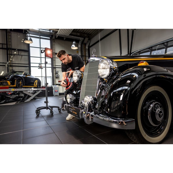 Ein Mitarbeiter poliert in einer Werkstatt die Front eines Oldtimer Mercedes mit einer Poliermaschine unter Einsatz eines LED Arbeitsstrahlers.