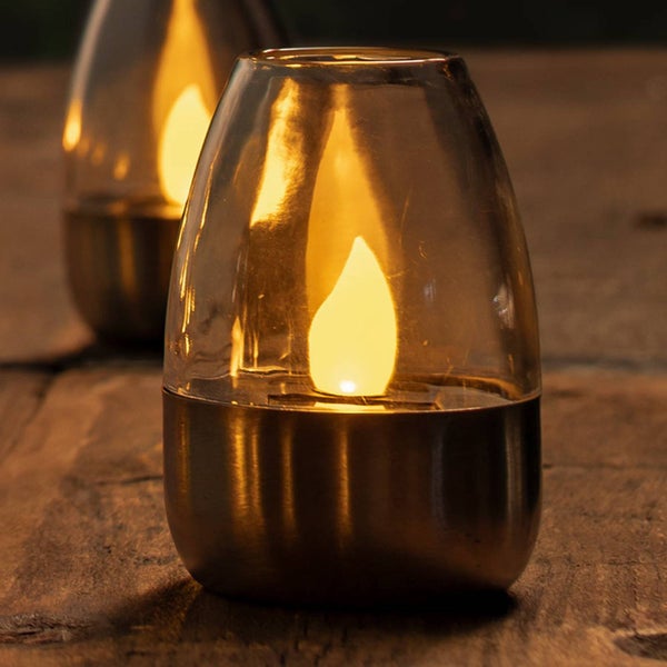 Dekorative Tischlaterne mit Glasaufsatz, Metallfuss und LED-Kerze auf einer Holzoberfläche.