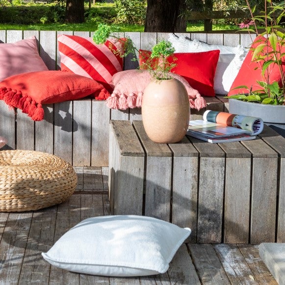 Gestaltungsideen für den Außenbereich mit Holzelementen, Kissen und Dekorationen.