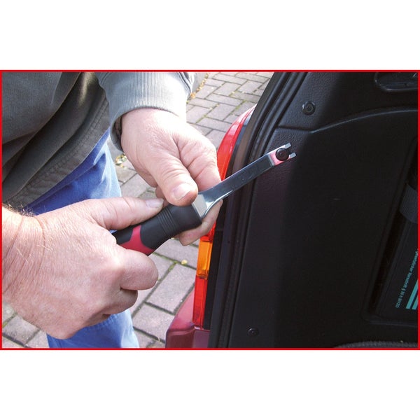 Eine Person benutzt ein Werkzeug zum Entfernen einer Befestigung aus einem Fahrzeug.