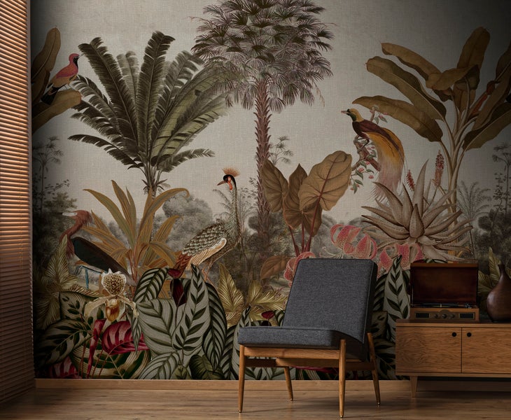 Wohnzimmer mit Vliestapete im Tropen Design mit exotischen Pflanzen und Vögeln, dazu ein grauer Sessel und eine Anrichte aus Holz.