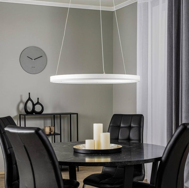 Moderne ringförmige LED-Pendelleuchte in Weiß über einem runden Marmortisch mit schwarzen Lederstühlen in einem modernen Esszimmer.