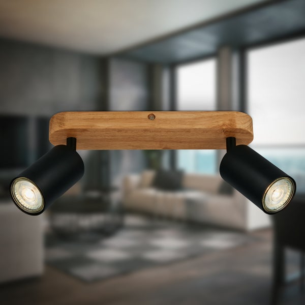 Zweiflammiger Deckenstrahler aus Holz und schwarzem Metall mit verstellbaren Spots in einem modern eingerichteten Wohnzimmer.