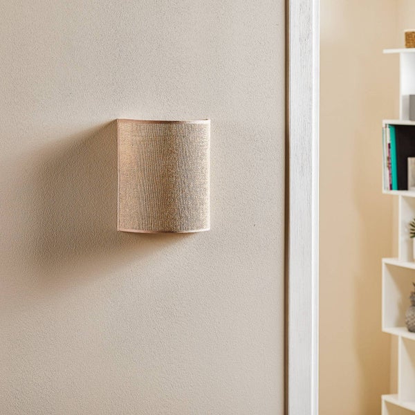 Moderne Wandleuchte mit halbrundem Schirm aus strukturiertem Stoff an einer Wand neben einem Regal.