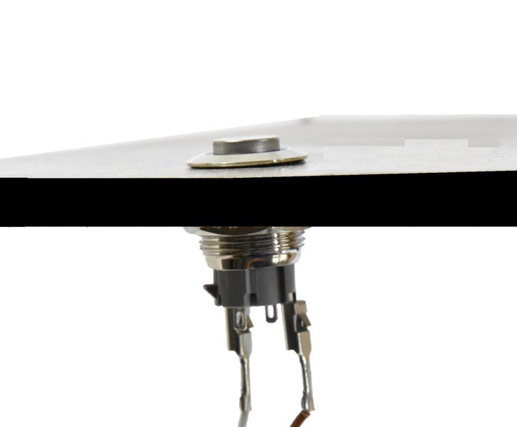 Drucktaster aus Metall, in einer Platte montiert, mit elektrischen Anschlüssen an der Unterseite.