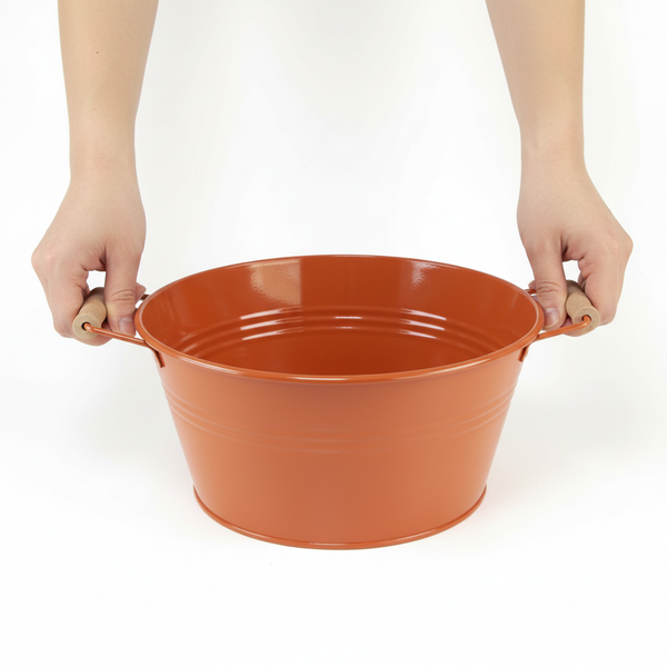 Orangene Metallwanne mit Holzgriffen, gehalten von zwei Händen.