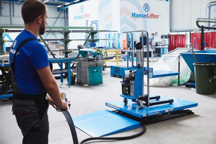 Ein Mitarbeiter bedient einen elektrischen HanseLifter Hubtisch mit Auffahrrampe in einer industriellen Werkstattumgebung.