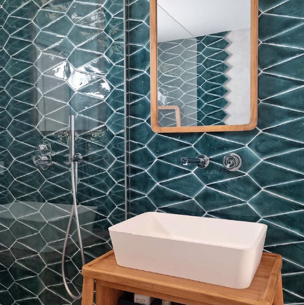 Modernes Badezimmer mit geometrischen Wandfliesen, weißem Aufsatzwaschbecken und Holzwaschtisch mit Spiegel.