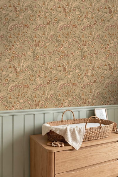 Vliestapete mit Waldtieren in einem Kinderzimmer über einer Wandtäfelung mit einem Wickelkorb aus Korbgeflecht auf einer Holzkommode.