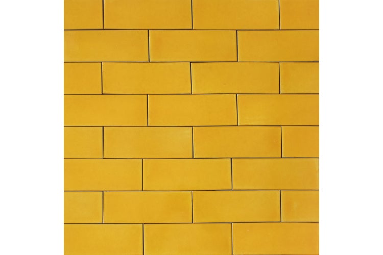 Gelbe Wandfliesen in rechteckiger Form im Mauerverband verlegt.