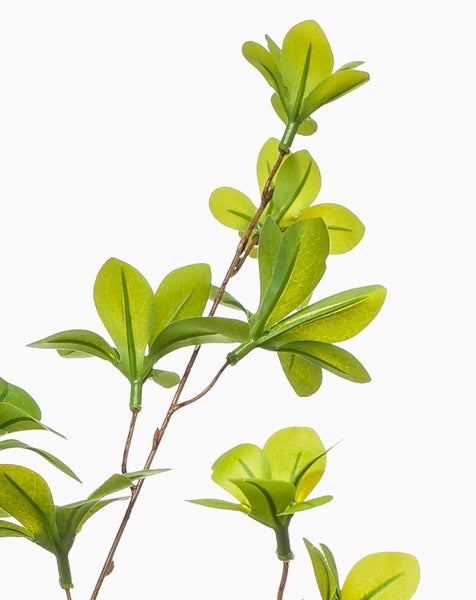 Künstlicher Zweig mit grünen Blättern zur Dekoration.