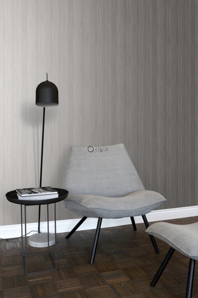 Wohnraum mit grauer Tapete in Holzoptik, Sessel, Fußhocker, Stehlampe und Beistelltisch