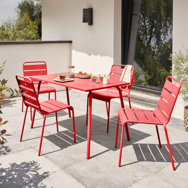 Modernes Gartenmöbel-Set aus rotem Metall mit einem rechteckigen Tisch und vier Stühlen auf einer hellen Steinterrasse.