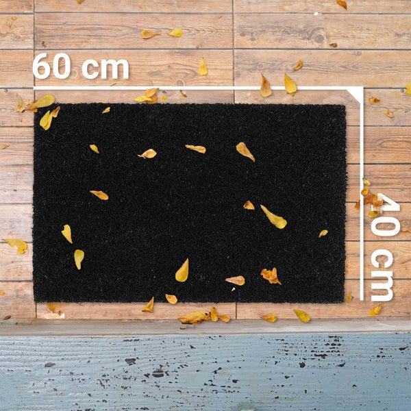 Schwarze Fußmatte mit schmutzigen Gummistiefeln im Eingangsbereich.