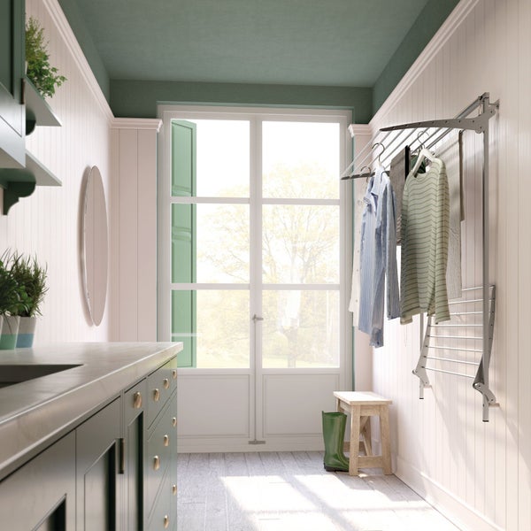 Wäschezimmer mit Waschtisch, Spiegel, Wäscheständer, Fenster und Accessoires für einen hellen und organisierten Eindruck.