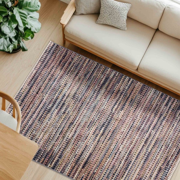 Ansicht von oben auf einen Teppich mit Muster, der in einem hellen Raum unter einem Sofa liegt.