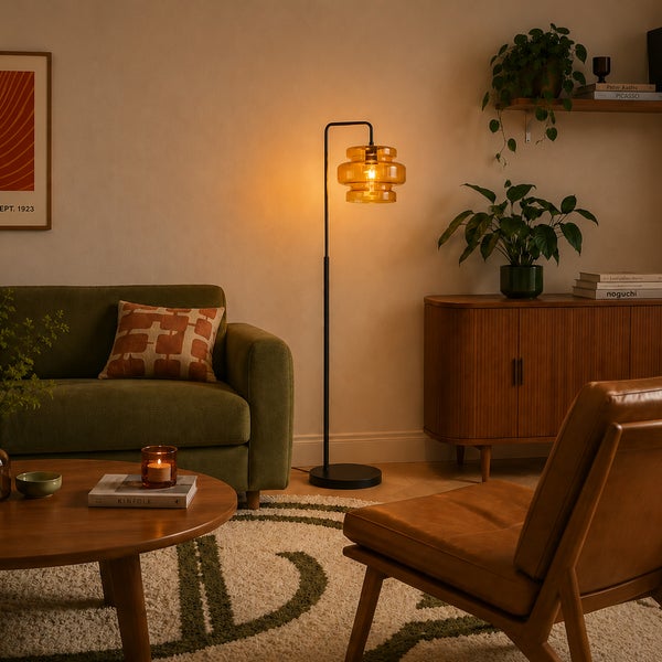 Moderne Stehlampe mit bernsteinfarbenem Glasschirm und schwarzem Metallgestell in einem gemütlich eingerichteten Wohnzimmer.