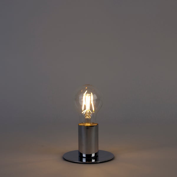 Klare LED-Filament-Glühbirne mit warmweißem Licht in einer silbernen Zylinderfassung auf rundem Standfuß.