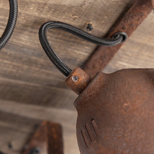 Detailaufnahme einer Lampe mit rostfarbenem Metallgehäuse und schwarzem Kabel