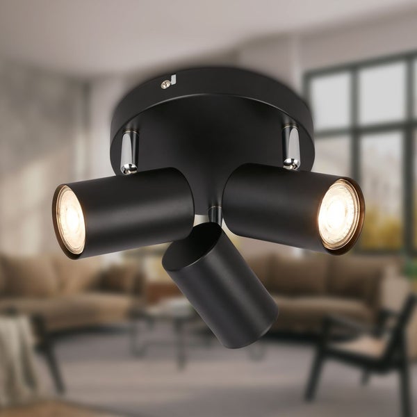 Dreiflammiger Deckenstrahler in Schwarz mit verstellbaren zylindrischen Spotköpfen in einem hellen Wohnzimmer.